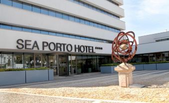 "a sculpture is placed in front of the entrance to a hotel named "" eia porto hotel "" with a large metal ball sculpture" at Sea Porto Hotel