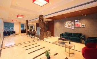 a modern , well - lit lobby with a green couch , coffee table , and framed pictures on the walls at National Park Residency