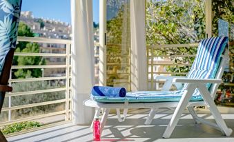 a blue and white striped lounge chair on a balcony , with a bottle of sunscreen nearby at Zeus