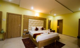 a large bed with a tufted headboard is in the center of a room with yellow walls at The River Front Resort