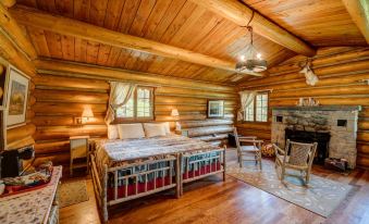 a cozy log cabin bedroom with a double bed , a fireplace , and a bathroom in the background at Diamond J Ranch