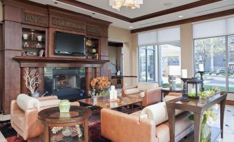 a spacious living room with various pieces of furniture , including a couch , chairs , and a television at Hilton Garden Inn Columbus/Edinburgh