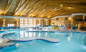 an indoor swimming pool with a wooden ceiling , surrounded by lounge chairs and umbrellas for relaxation at Thumper Pond Resort