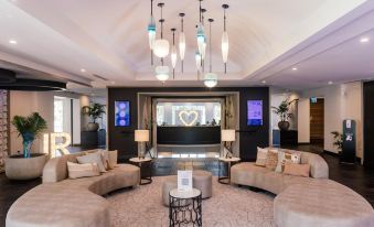 a modern living room with a large couch , chairs , and a tv . also a dining table in the room at Joondalup Resort