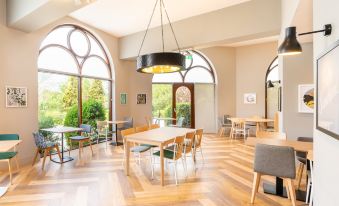 a dining room with wooden floors , a large dining table surrounded by chairs , and several potted plants at Holiday Inn Gloucester - Cheltenham