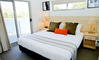 a large bed with a white comforter and multiple pillows is in a room with a sliding glass door at Jacana Apartments