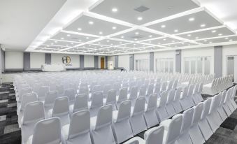 an empty conference room with white chairs arranged in rows and a large screen on the wall at Hotel Frontera Clásico