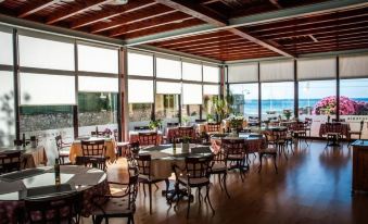 an empty restaurant with wooden floors and tables , set up for dining , with large windows offering views of the ocean at Hotel Don Pepe