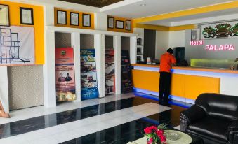 a reception area in a hotel with a man standing behind the counter and various advertisements on the walls at Hotel Palapa