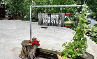 a sign for guest parking is displayed above two large logs with a red flower pot in front at Amish Country Comfort