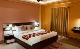 a large bed with a white and red blanket is in the middle of a room with orange walls at The Loft Hotel, Siliguri