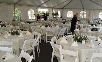 a large white tent set up for a wedding reception , with tables and chairs arranged in a circular pattern at Lafayette Inn