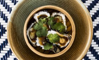 a bowl filled with oysters on a woven table mat , creating a visually appealing presentation at Anchorage Port Stephens