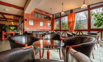 a cozy and well - lit restaurant with multiple chairs and tables arranged for dining , surrounded by windows that allow natural light to enter at Hotel Golfer