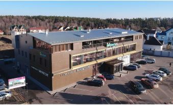 an aerial view of a large building with multiple cars parked in front and trees in the background at L'Hotel