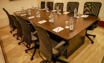 a conference room with a long table and multiple chairs arranged for a meeting , along with bottles of water on the table at Emporio Hotel