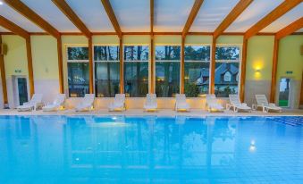an indoor swimming pool with a large window overlooking the surrounding area , and several lounge chairs surrounding the pool at Millennium Spa