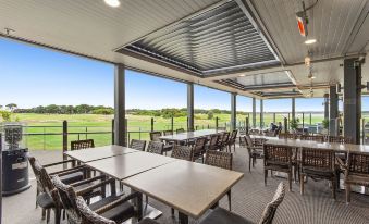 a restaurant with tables and chairs , a bar , and a view of the golf course at 13th Beach Golf Lodges