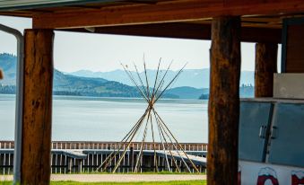 a wooden structure with a long pole and sticks in front of a body of water at Big Arm Resort