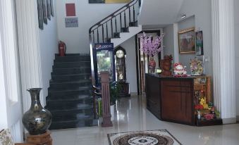 a white foyer with a staircase leading up to the second floor , where a dining table and chairs at Hotel Nguyen Ngoc