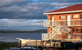 a red brick building with a balcony and a car parked in front of it , next to a body of water at The Waterloo Hotel