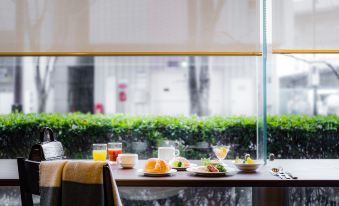 a dining table set with a variety of food items , including sandwiches , drinks , and fruits at Mitsui Garden Hotel Okayama