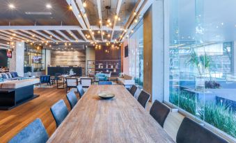 a large wooden dining table surrounded by chairs in a room with a high ceiling at Four Points by Sheraton Puebla