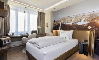 a large bed with white linens is in a room with wooden floors and a chair at Hotel Innsbruck