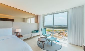 a modern hotel room with a large window , a blue chair , and a round rug on the floor at Radisson Blu Aruba