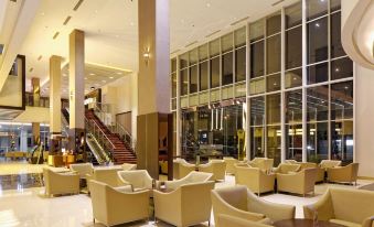 a spacious room with multiple beige chairs and couches arranged around a coffee table , creating a comfortable seating area at ASTON Purwokerto Hotel & Convention Center