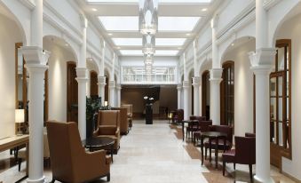 a modern , well - lit lobby with multiple seating areas and a chandelier hanging from the ceiling at Park Plaza Victoria Amsterdam