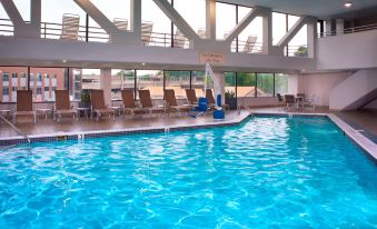 an indoor swimming pool with a large glass window , providing a view of the surrounding area at Marriott East Lansing at University Place