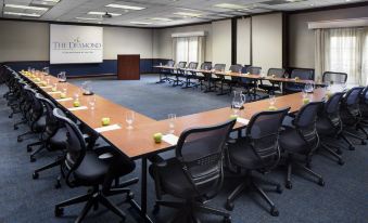 a conference room with a large table surrounded by chairs and a sign on the wall at Desmond Hotel Malvern, a DoubleTree by Hilton