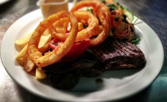 a plate of food on a dining table , consisting of steak , onion rings , and fries at Aberdour Hotel, Stables Rooms & Beer Garden