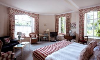 a large bedroom with a red and white striped bedspread , a television , and multiple chairs at Castle Hotel