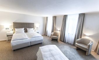 a hotel room with two beds , one on the left and one on the right side of the room at Bayerischer Hof