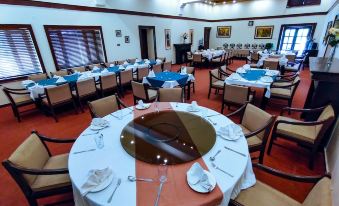 a large , well - lit room with multiple dining tables set for a meal , each table having its own unique arrangement of cutlery and nap at Lockwood Hotel Murree