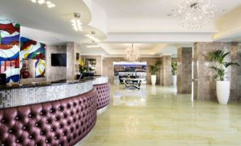 a modern hotel lobby with a marble floor , a reception desk , and a large painting on the wall at Swan River Hotel