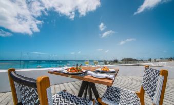 a table with plates of food and wine glasses is set up on a patio overlooking the ocean at Ocean V Hotel