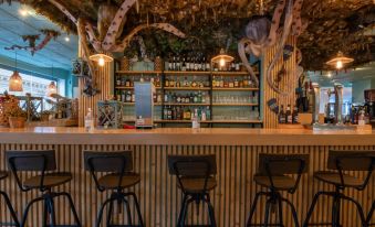 a bar with a wooden counter and stools , surrounded by shelves filled with various bottles and glasses at Hotel Bahía de Vigo