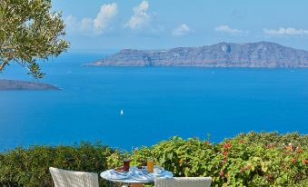 a beautiful view of the ocean from a balcony , with a table and chairs set up for dining at Belvedere Suites