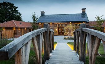 a wooden bridge leading to a house with a large tree and lights on the roof at Retreat East
