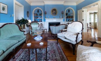 a cozy living room with blue walls , hardwood floors , and various pieces of furniture such as chairs , a couch , and a coffee table at Hillcrest Mansion Inn