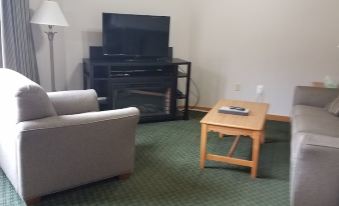 a living room with a couch , chair , and coffee table in front of a television at Creekside Village