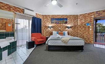 a hotel room with a bed , blue couch , and a chair , all set against a brick wall at Airport Clayfield Motel