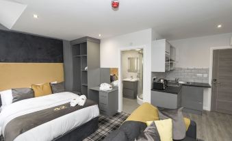 a modern hotel room with a bed , kitchenette , and living area , all decorated in grey and yellow colors at 42 Apart-Hotel