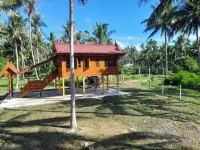 Traditional Thai wooden house on stilts set in a coconut orchard near the beach