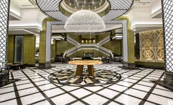 a grand hotel lobby with a marble floor , a round dining table , and a chandelier hanging from the ceiling at Ayla Grand Hotel Al Ain