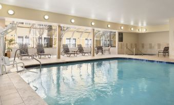 an indoor swimming pool surrounded by lounge chairs and tables , providing a relaxing atmosphere for guests at Homewood Suites by Hilton Columbus - Hilliard