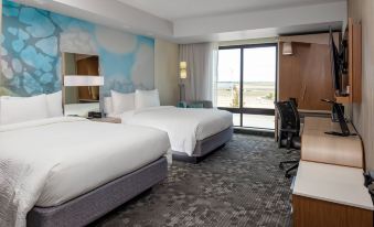 a modern hotel room with two beds , a desk , and a window offering a view of the city at Courtyard Pasco Tri-Cities Airport